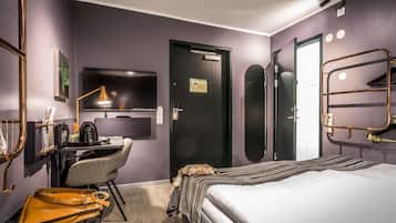 Una habitación de hotel moderna con cama, escritorio, silla y televisor.