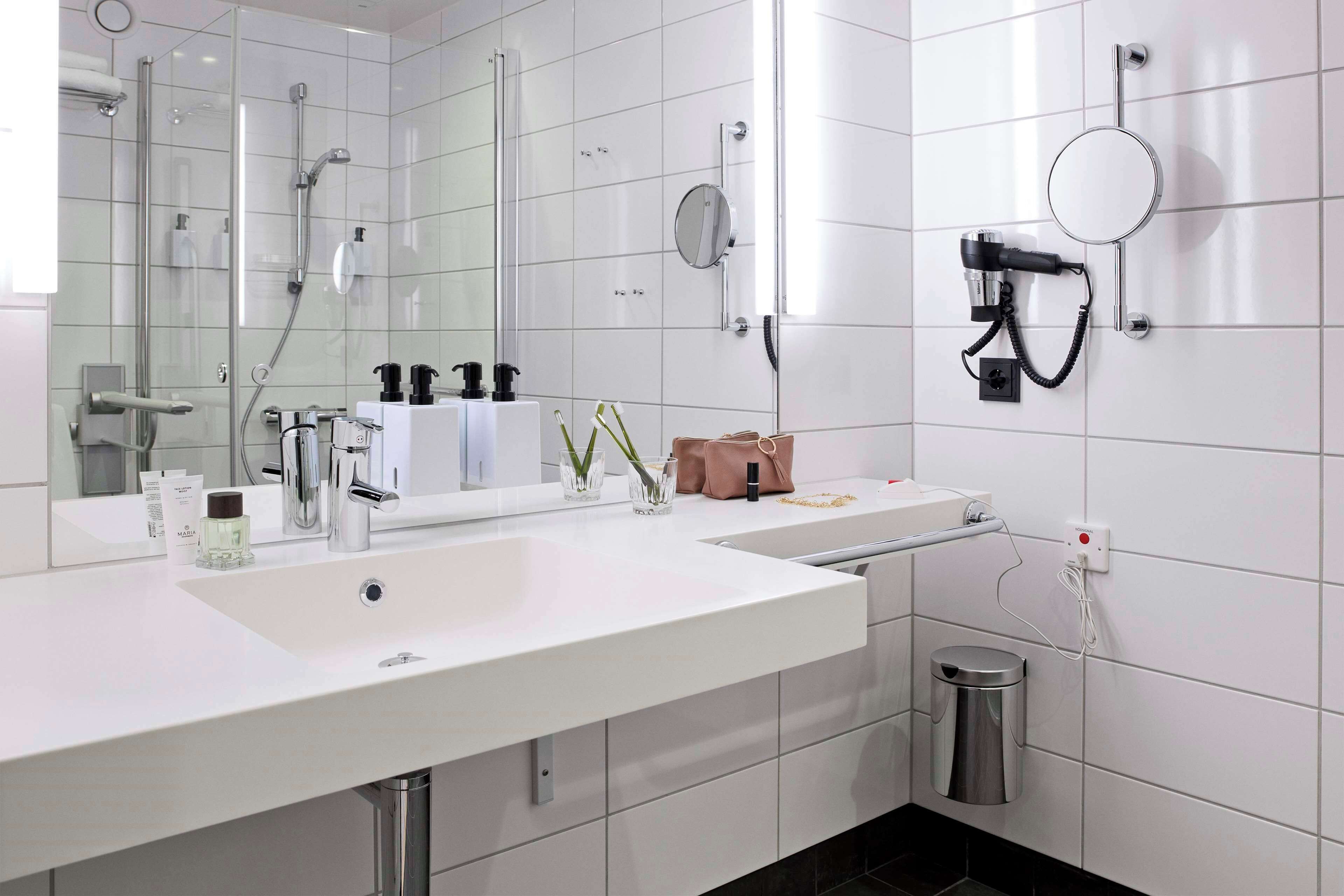 Un baño moderno con un espejo grande, ducha y tocador con lavabo.