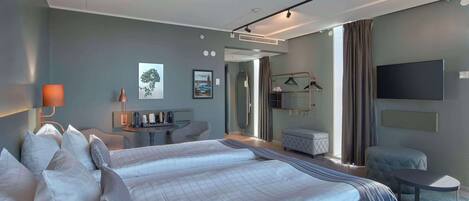 Habitación de hotel con cama, mesitas de noche, escritorio, silla, televisión y ventana con cortinas.