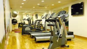 Un gimnasio con cintas de correr, elípticas y un espejo grande.