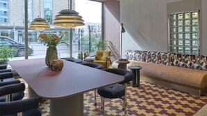 A modern interior with a long table, multiple chairs, a sofa, and a patterned rug. - Scandic Malmen (Stockholm)