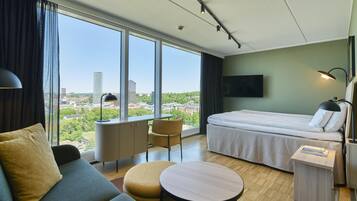 Habitación de hotel con cama, sofá, mesa redonda y vistas a la ciudad.