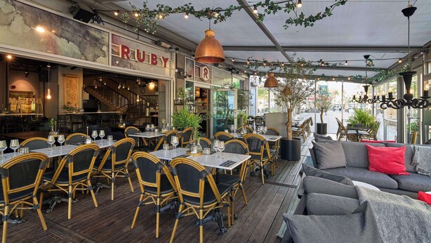 An outdoor dining area with tables and chairs, a bar area, and a seating area with a sofa. - Scandic Rubinen (Gothenburg)