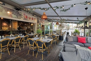 An outdoor dining area with tables and chairs, a bar area, and a seating area with a sofa. - Scandic Rubinen (Gothenburg)