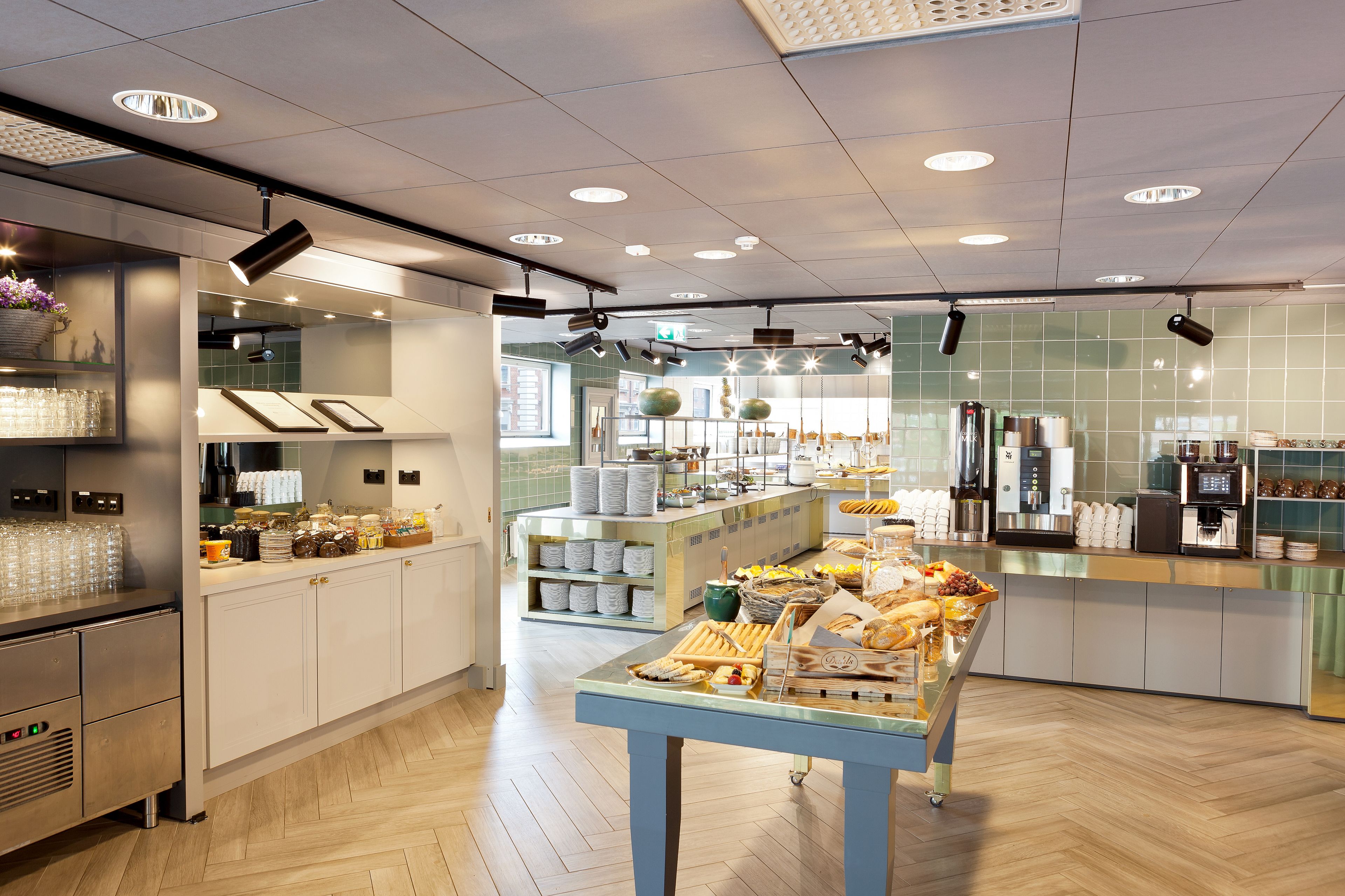 Eine moderne Küche mit einer zentralen Kochinsel, auf der Speisen, eine Kaffeestation und ein Kühlschrank präsentiert werden.