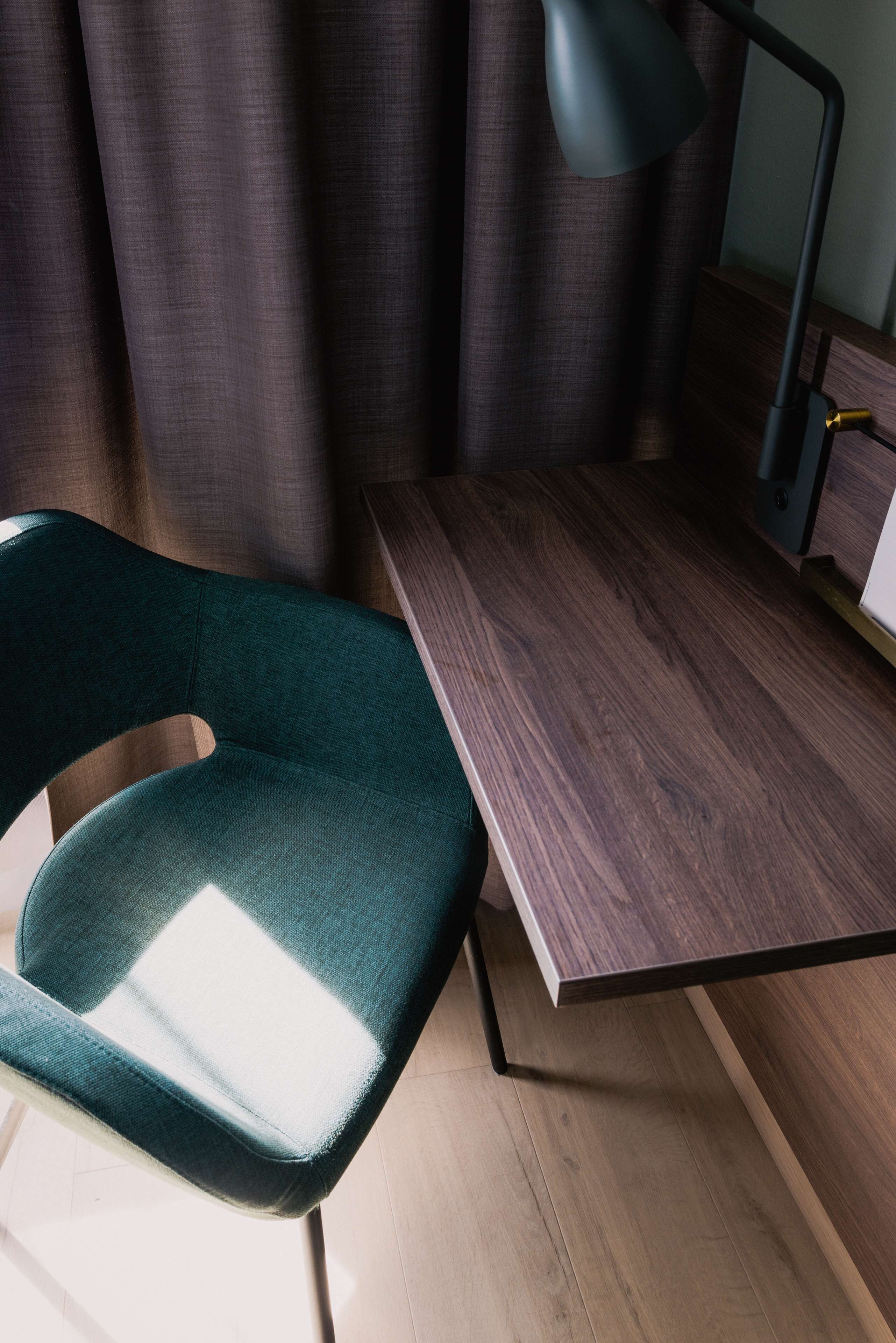 Una habitación moderna con un escritorio de madera y una silla verde.