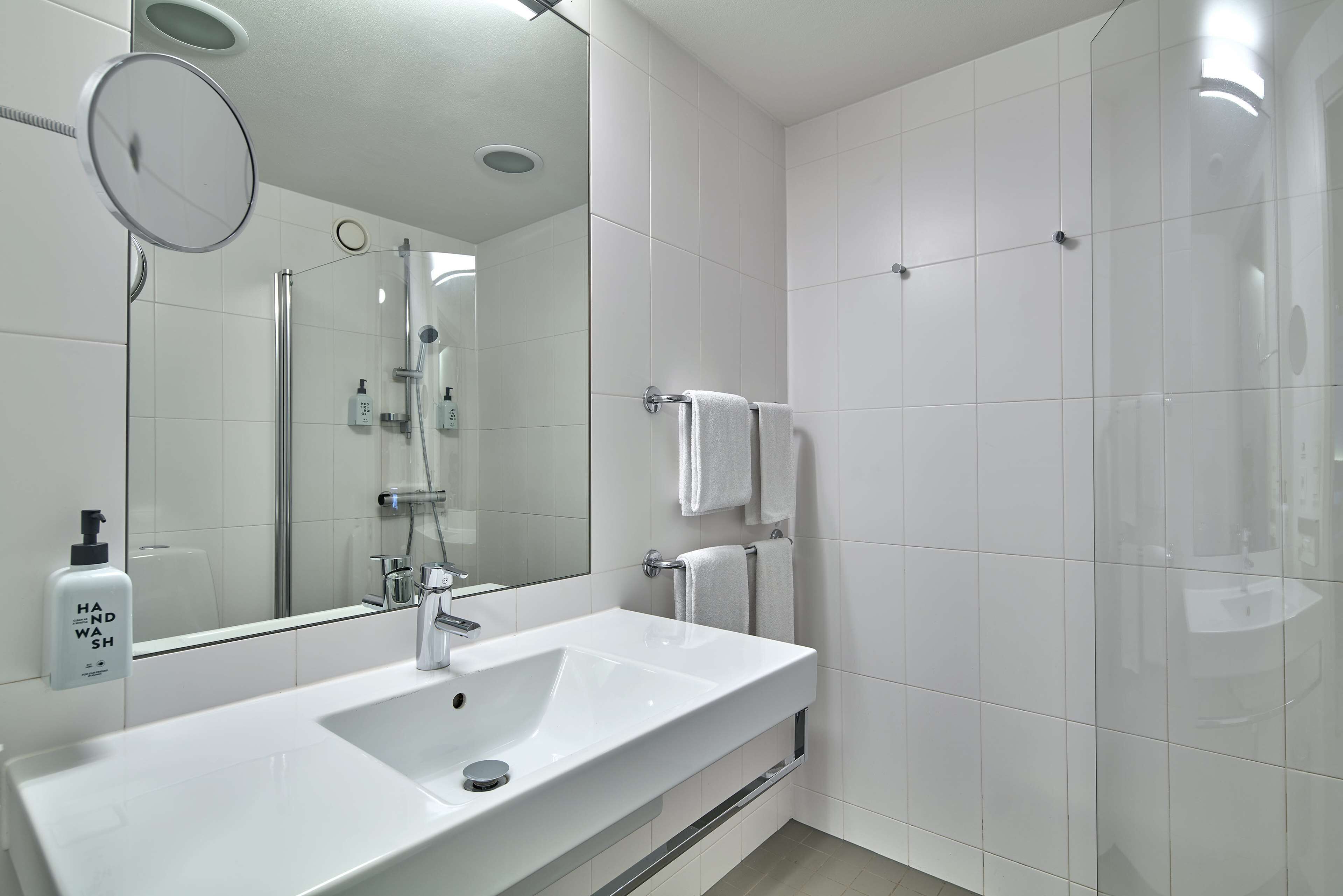 A modern bathroom with a white sink, a mirror, and a glass shower enclosure.