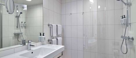 Un baño moderno con un espejo grande, lavamanos doble, ducha e inodoro.