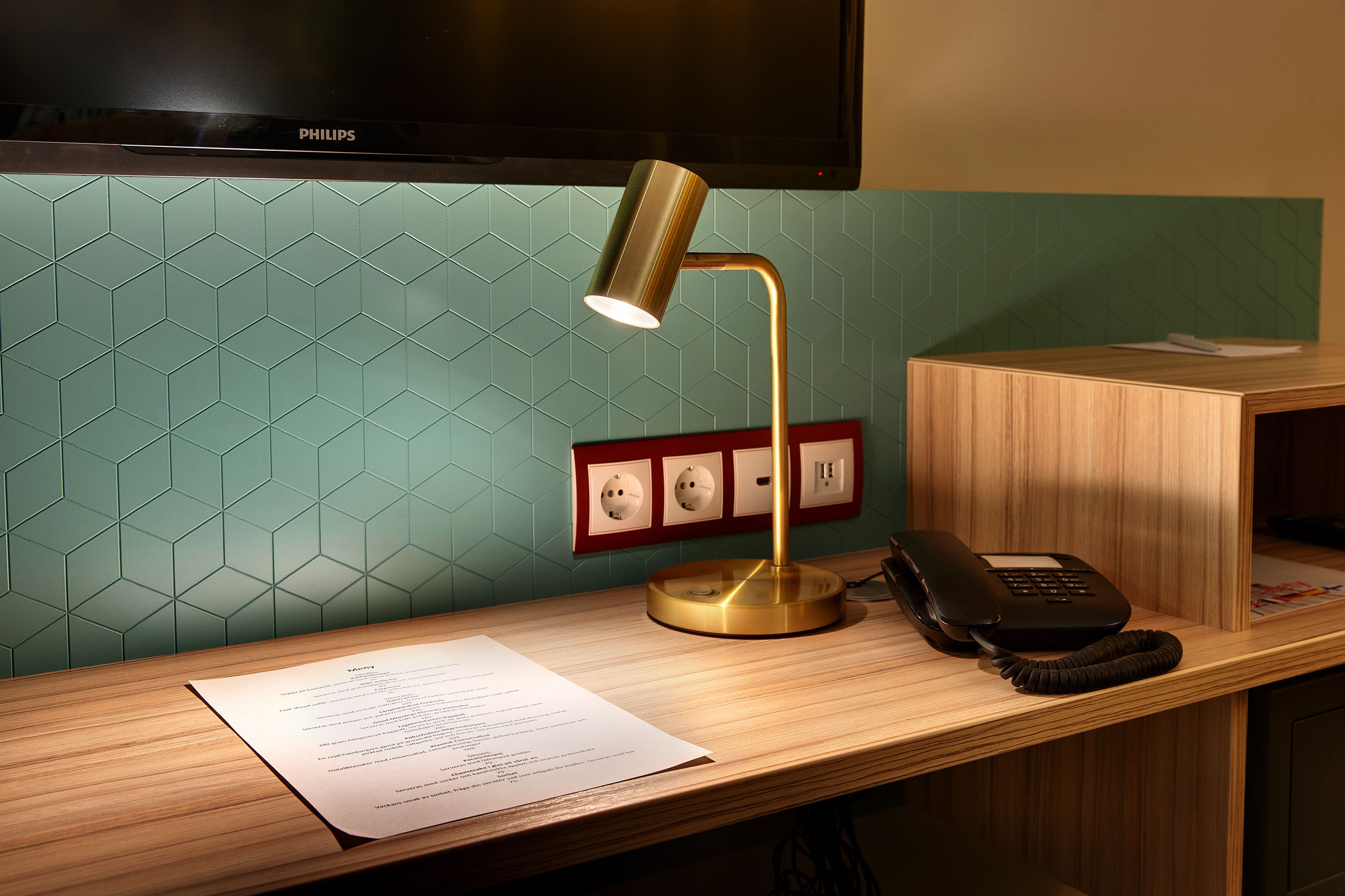 Een bureau met een lamp, telefoon en een menukaart.