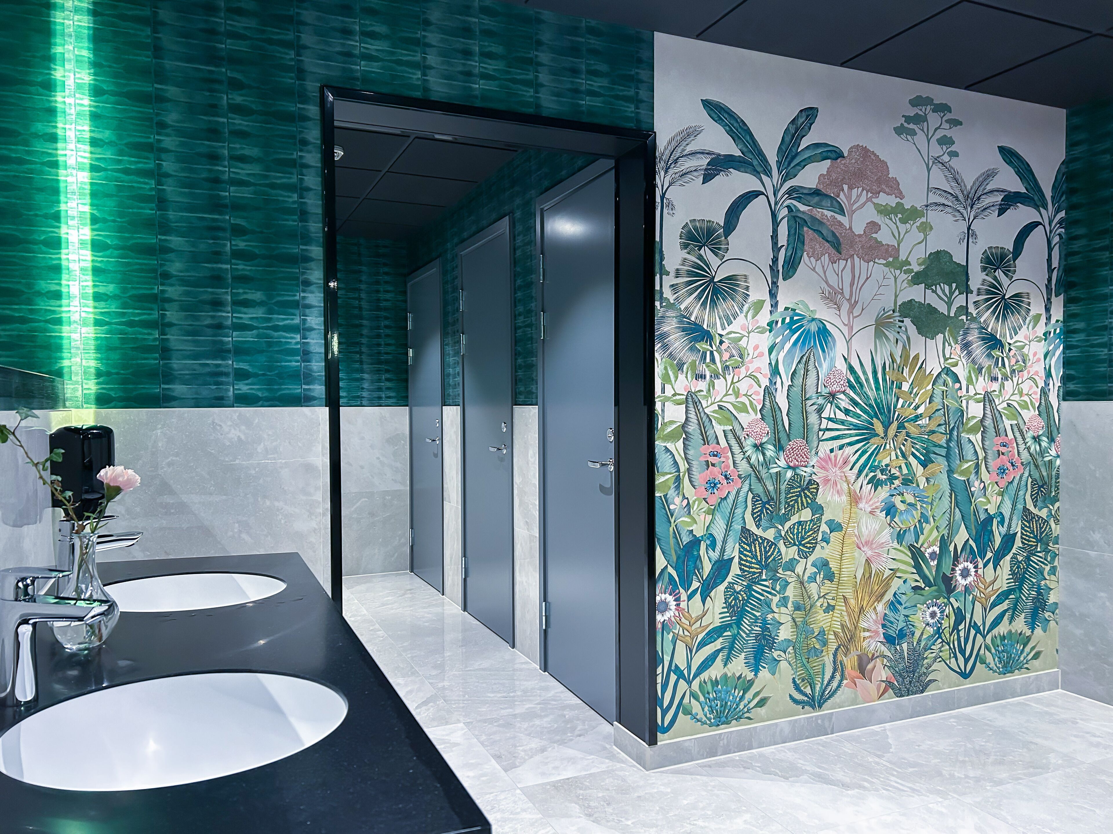 Un baño con dos lavamanos, un espejo y una puerta que da a un pasillo.