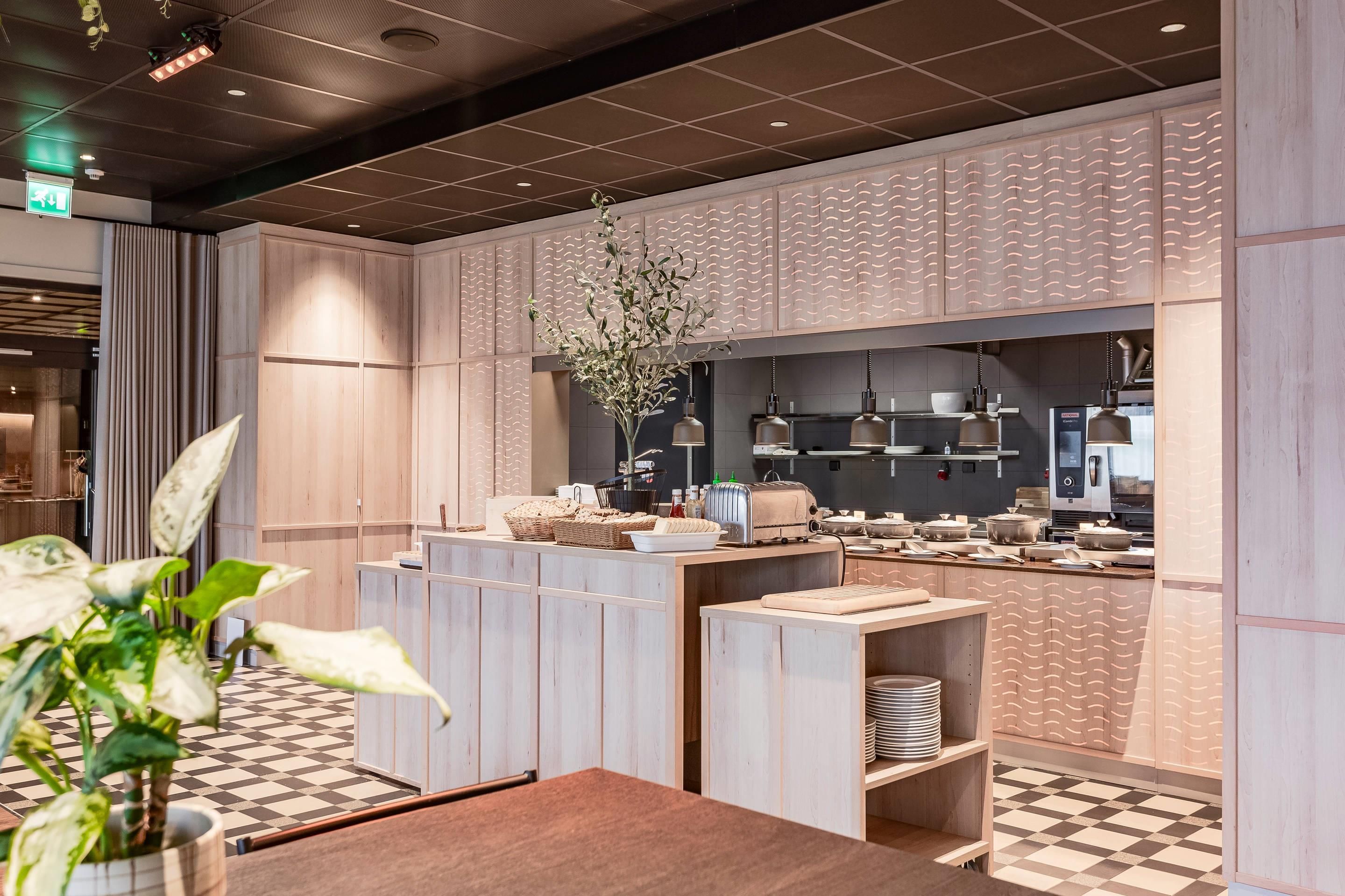 Een moderne keuken met houten kastjes, een centraal eiland en hangende lampen.