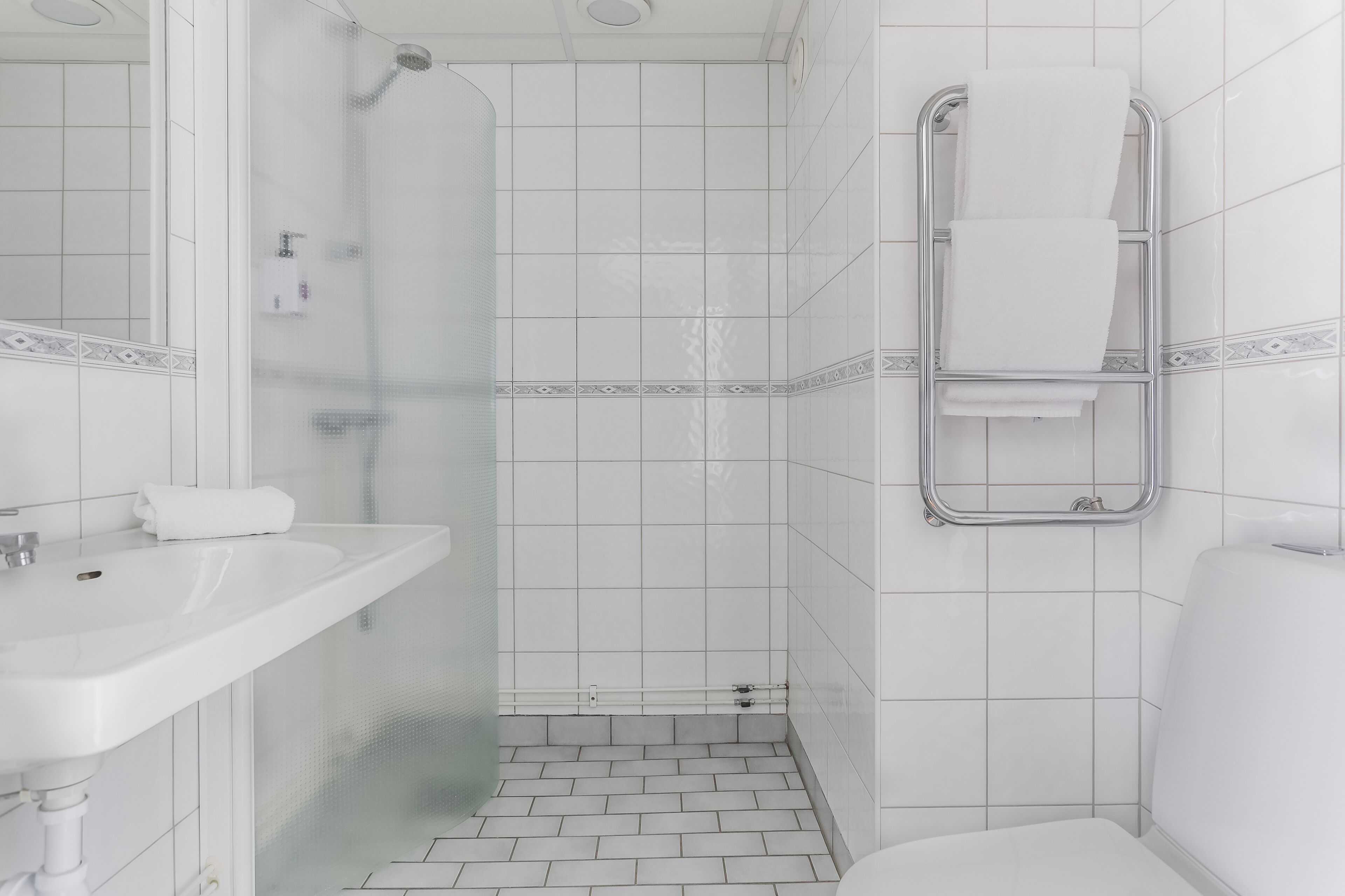 A bathroom with a white sink, a glass shower enclosure, and a towel rack.