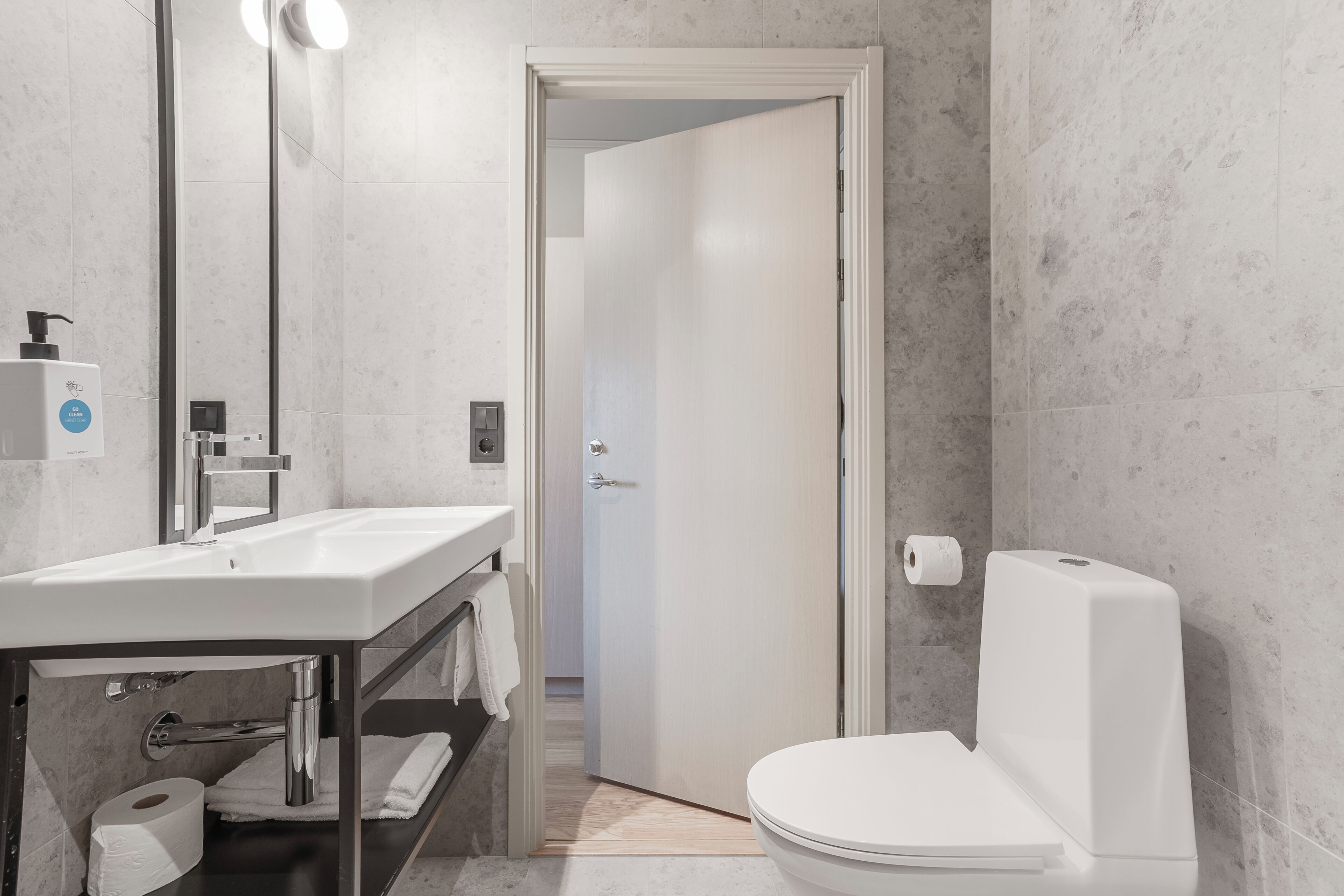 Un baño moderno con un lavabo, espejo y retrete blancos.