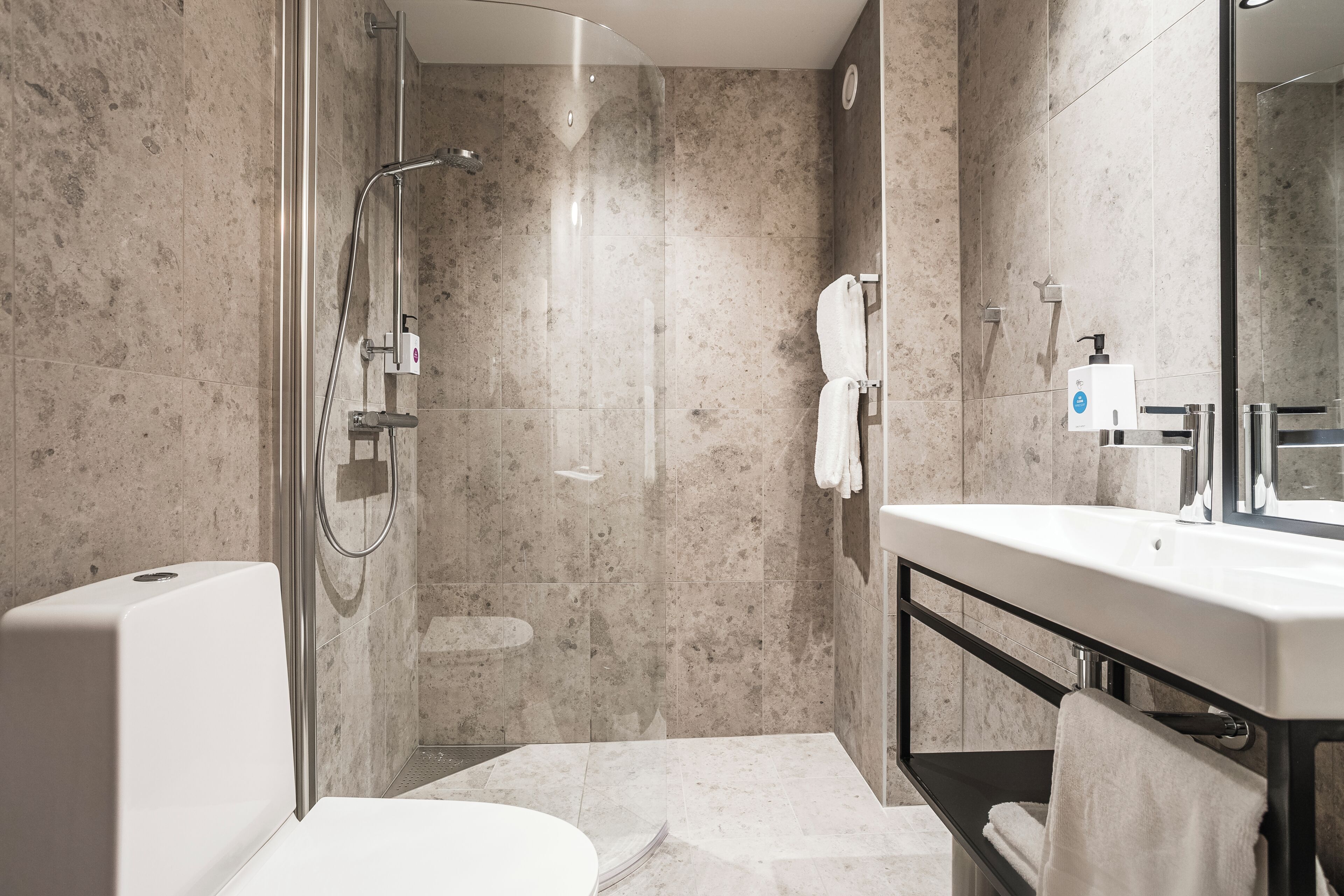 A modern bathroom with a glass-enclosed shower, a white bathtub, a large mirror, and a white sink.