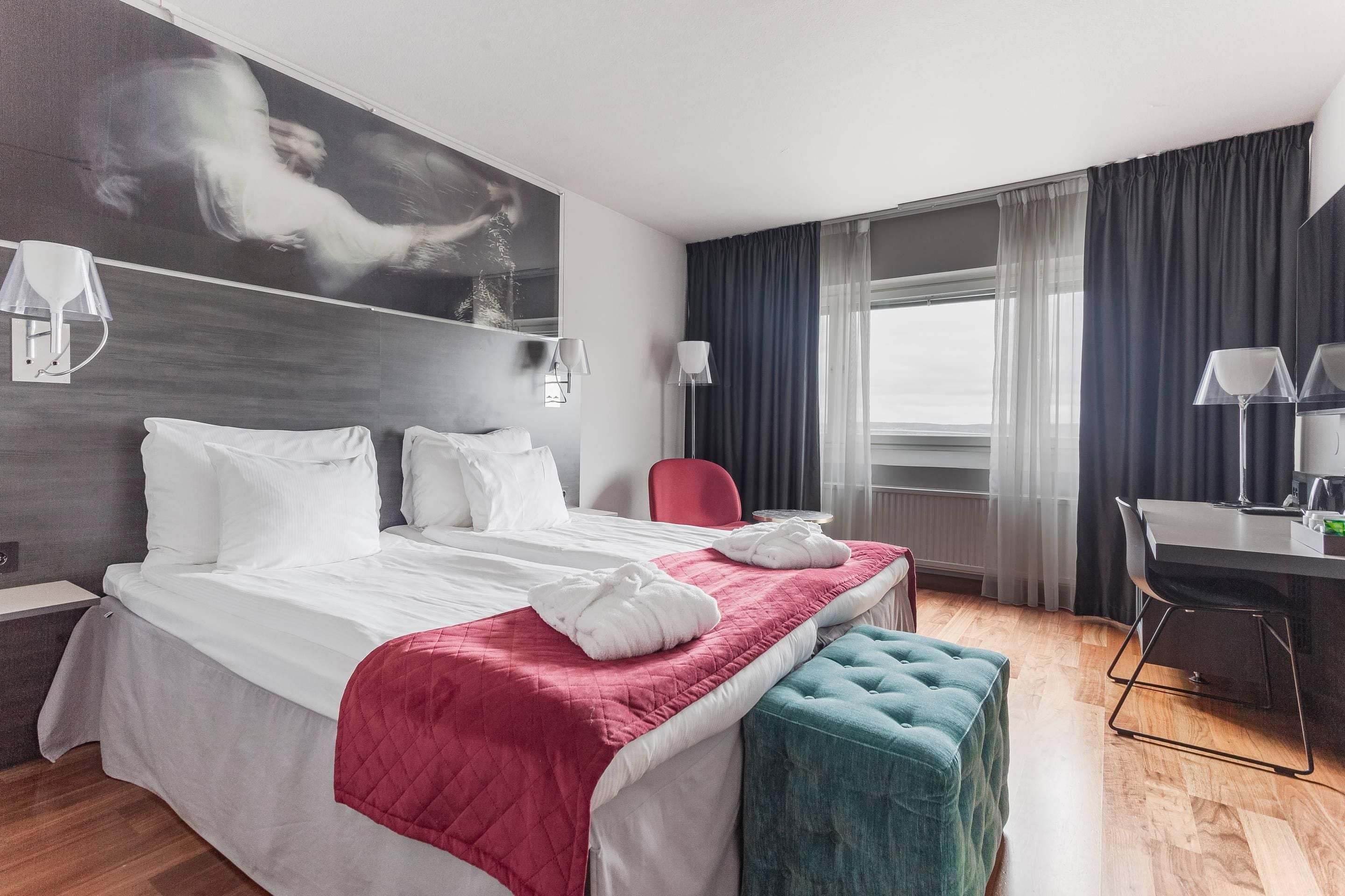 Una habitación de hotel con una cama grande, un escritorio y vistas a la ciudad.