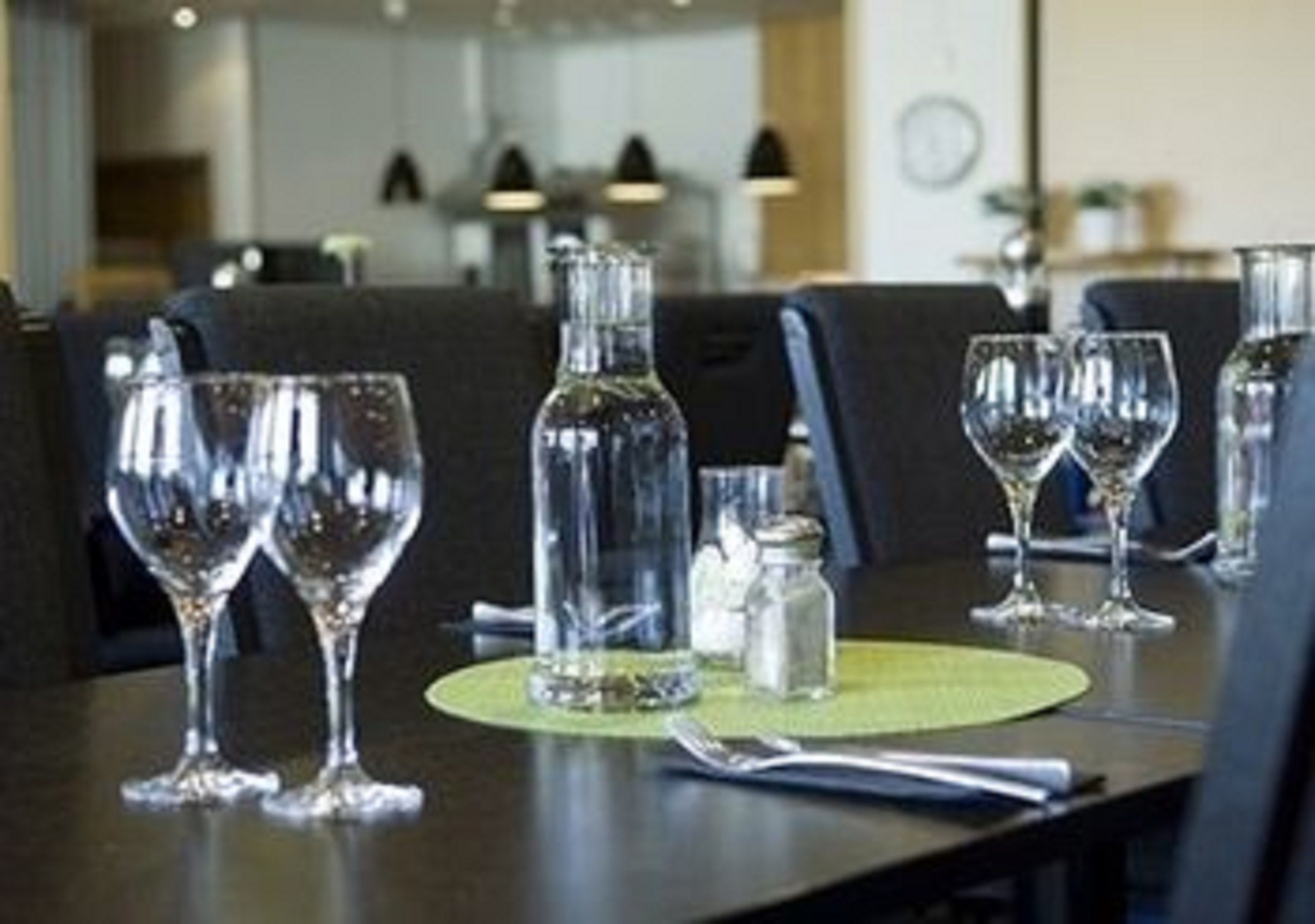 A dining table with empty wine glasses and a bottle, a salt shaker, and a napkin.