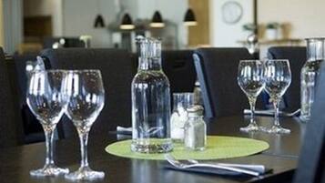 Une table à manger avec des verres à vin vides et une bouteille, un salier et une serviette.