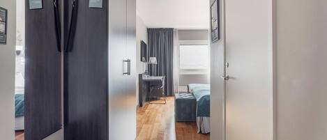A modern hotel room with a wooden floor, a bed, a desk, and a large mirror.