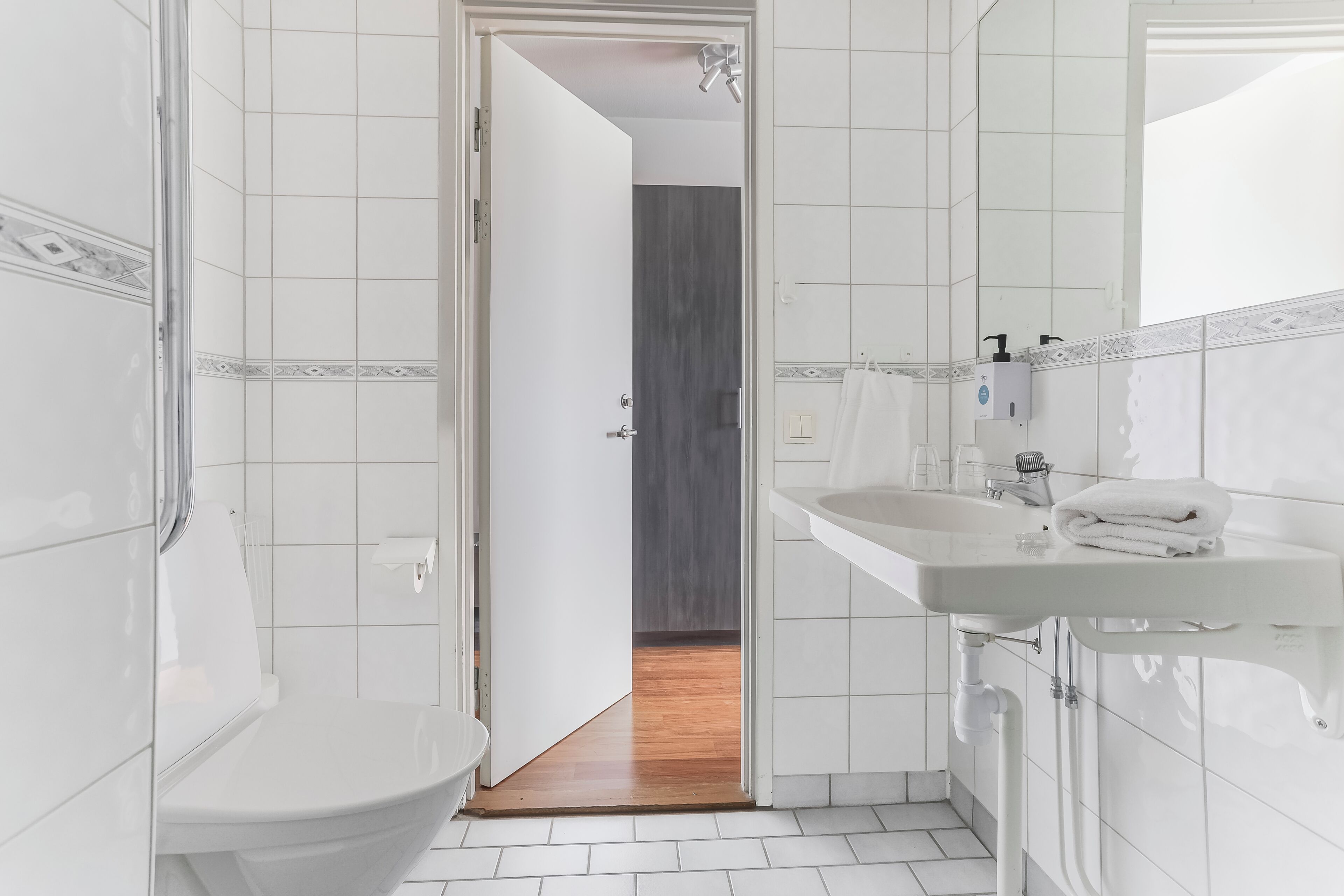 Un baño con lavamanos blanco, inodoro y zona de ducha.