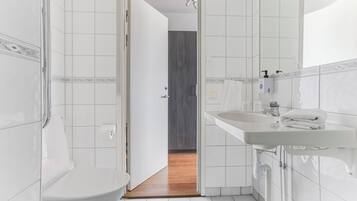 Een badkamer met een wit wastafel, toilet en douchehoek.