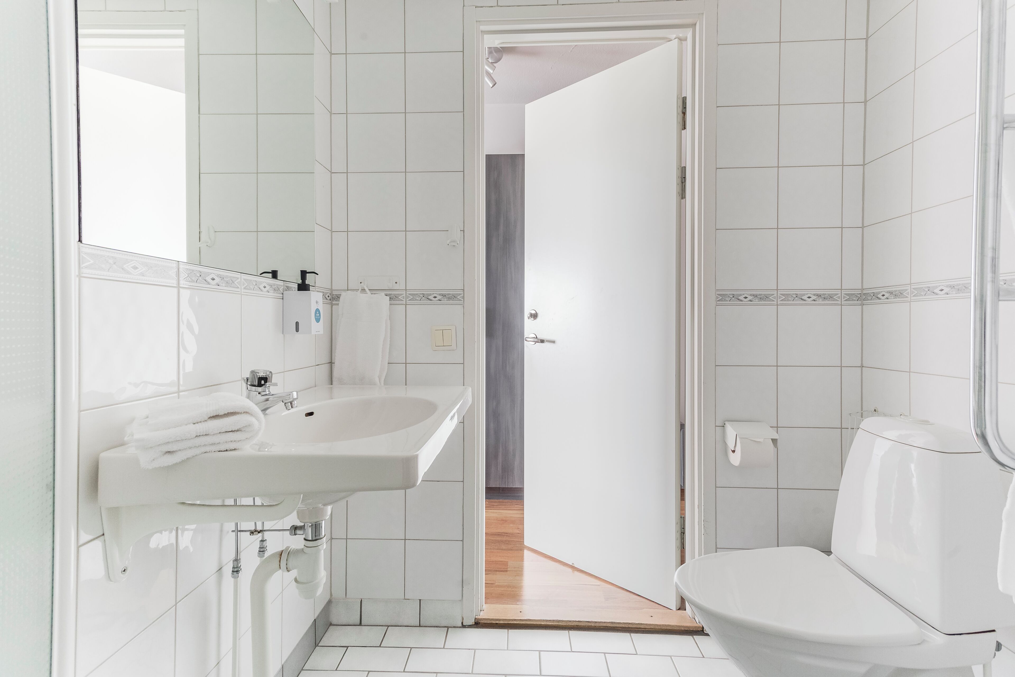 Un baño con lavamanos, inodoro y espejo.