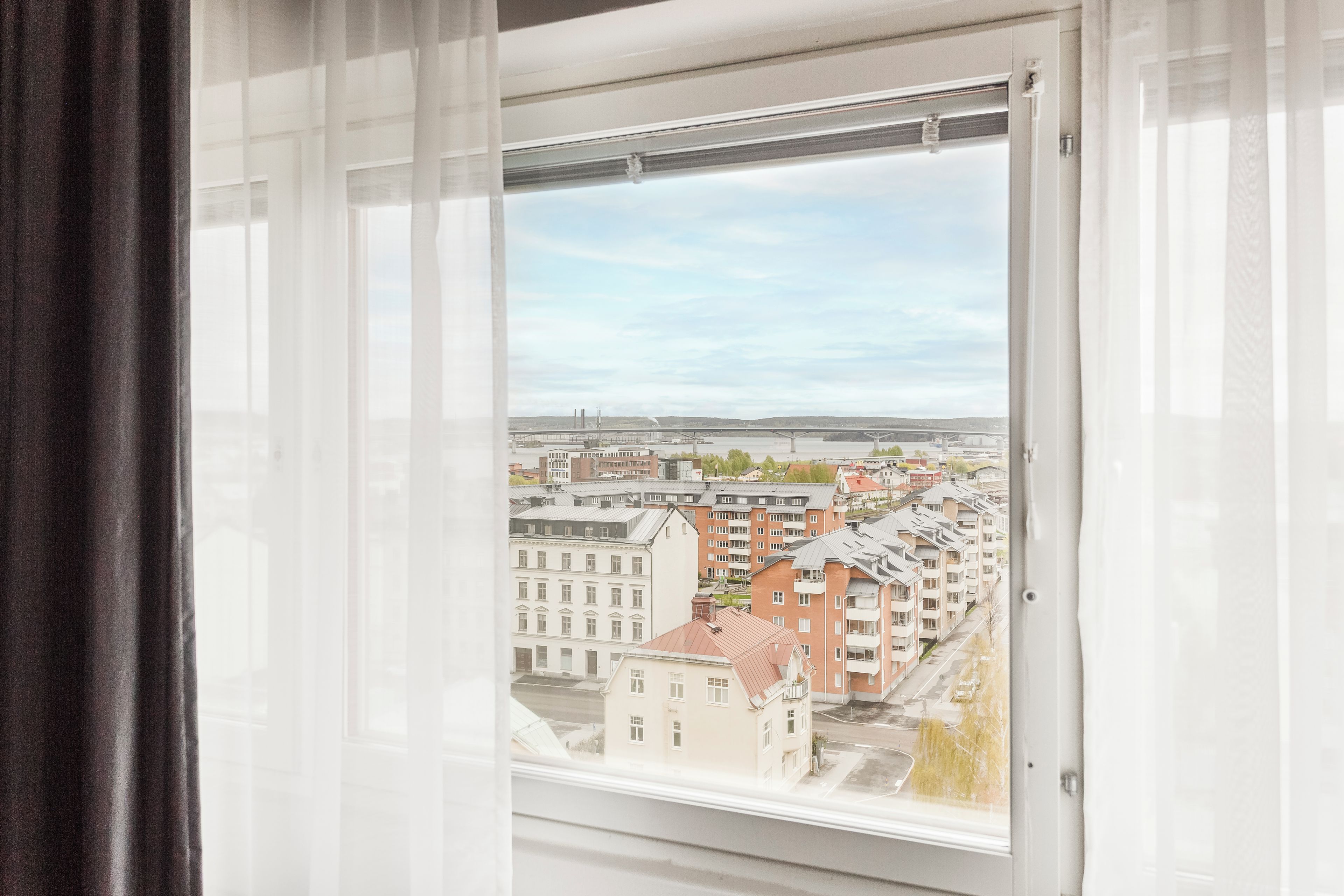 A window with a view of buildings and a clear sky.