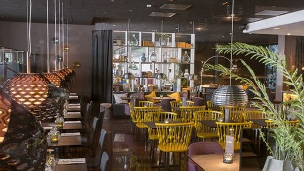 A restaurant interior with yellow chairs, dark wooden tables, and a glass display case with various items. - Quality Hotel Sundsvall (Sundsvall)