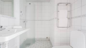 A bathroom with a white sink, a shower, a toilet, and a mirror.