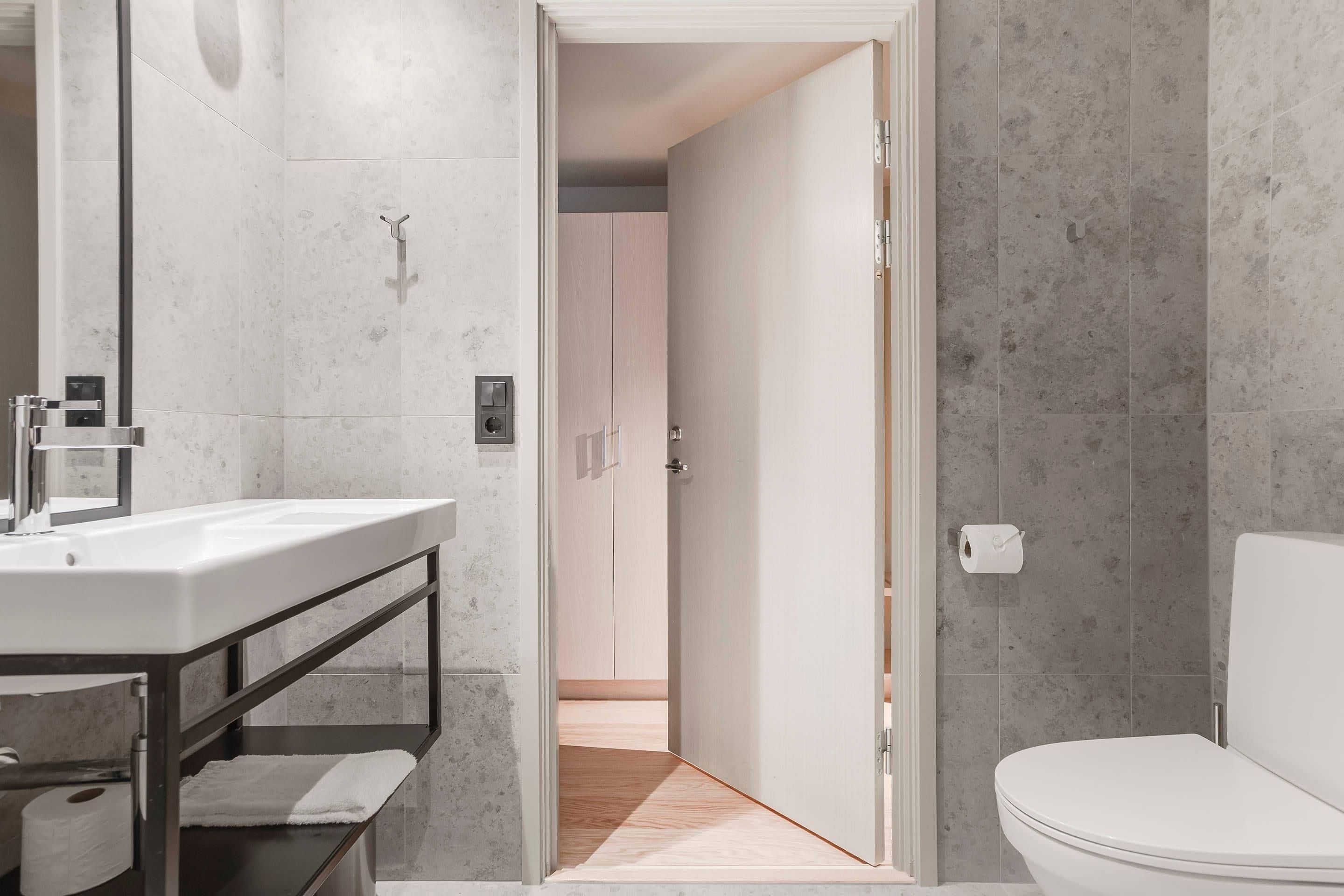 A modern bathroom with a white sink, mirror, and toilet.