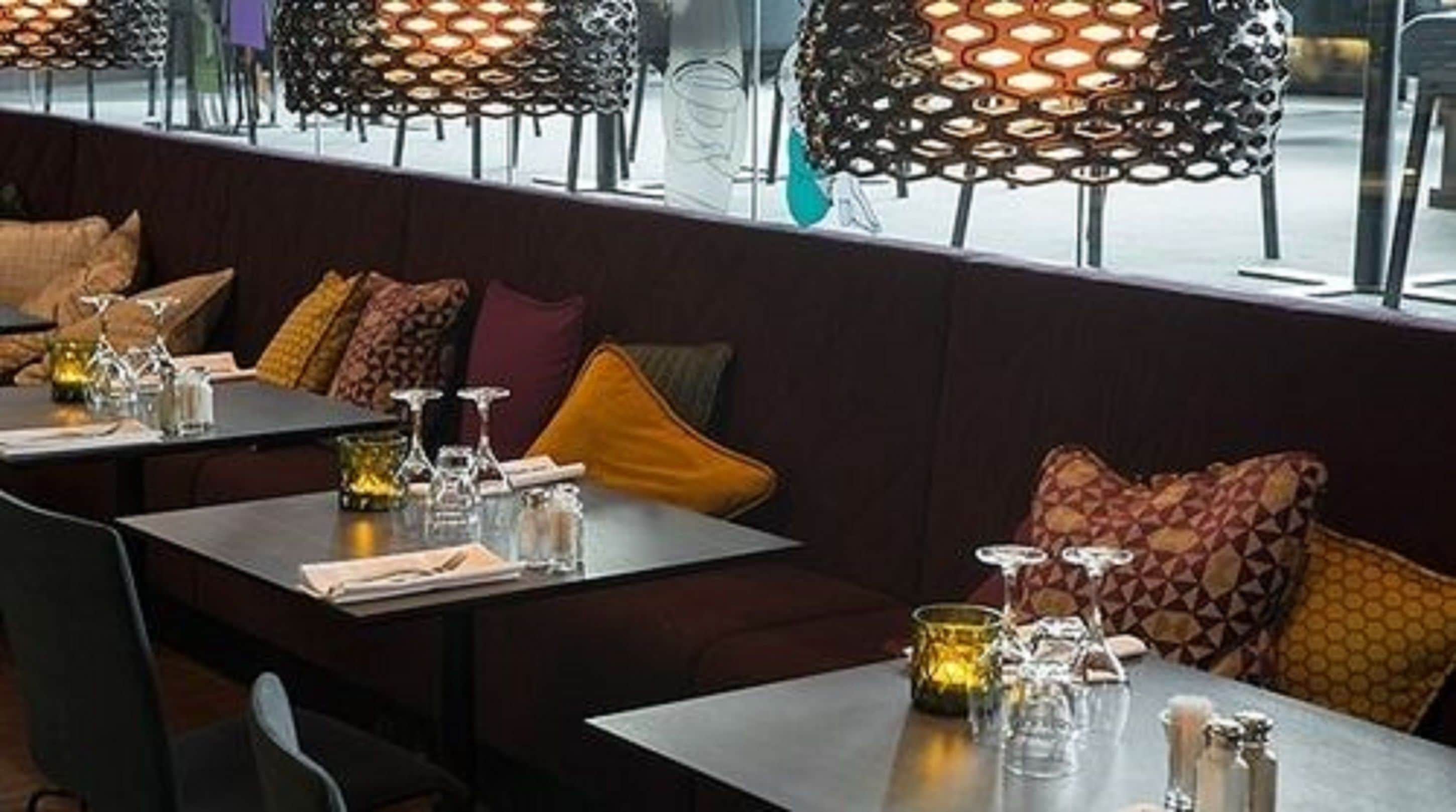 Interior de restaurante con cabinas, mesas y mesas iluminadas con velas.