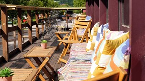 An outdoor seating area with wooden chairs and tables, a rainbow flag, and a view of the landscape. - Quality Hotel Sundsvall (Sundsvall)