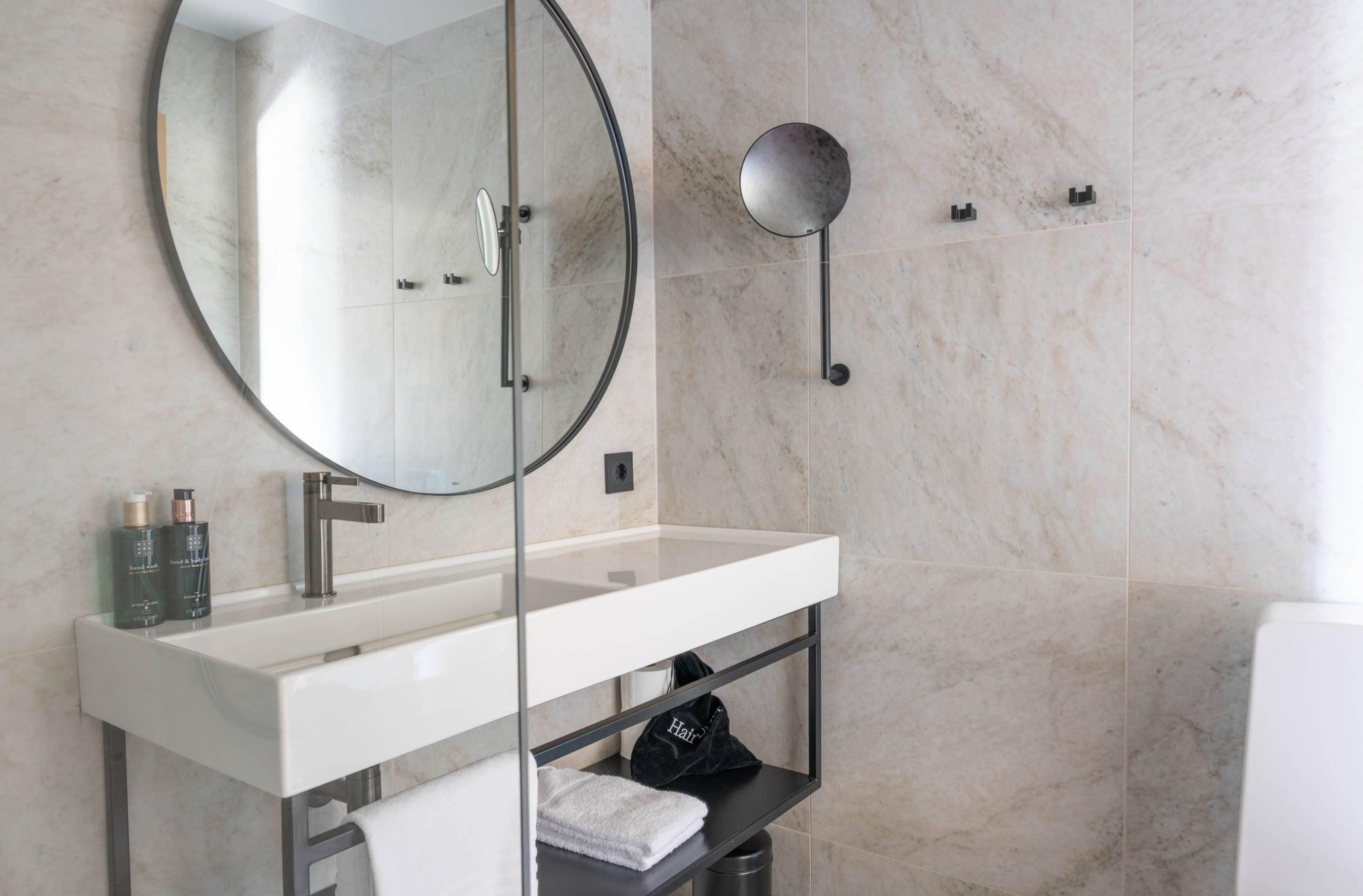 Un baño moderno con un espejo grande, un tocador blanco y un perchero para toallas.