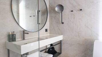 A modern bathroom with a large mirror, a white vanity, and a towel rack.