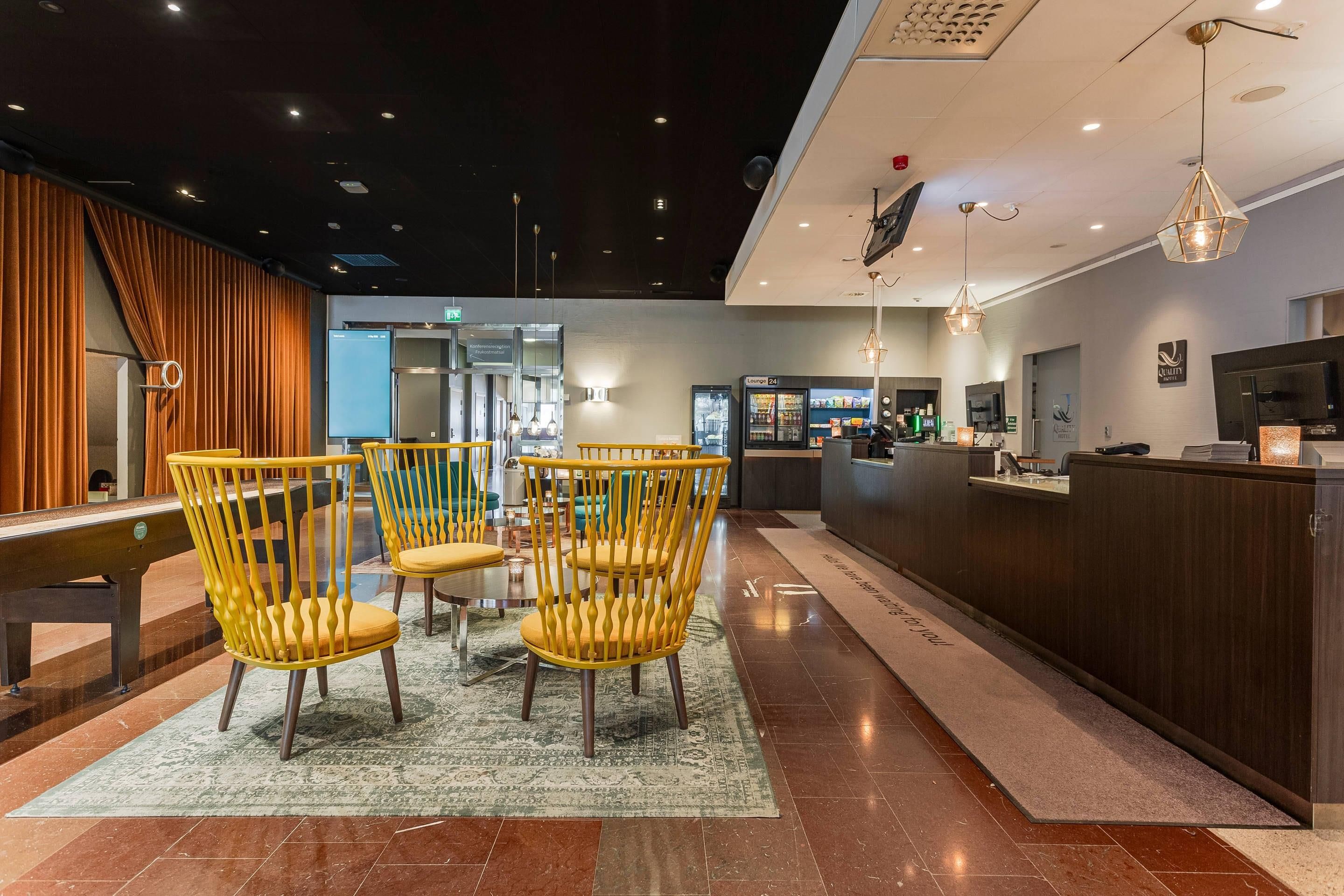 Eine Hotelhalle mit Rezeption, einer Sitzecke mit Stühlen und einer Kaffeemaschine.