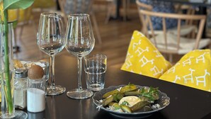 A restaurant interior with tables set for dining, clear glasses, and a plate of food. - Best Western Hotel Halland (Kungsbacka)