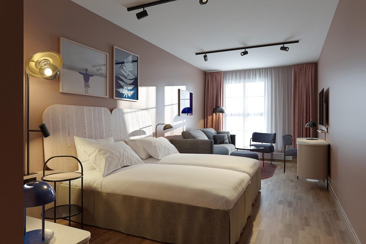 Une chambre d’hôtel moderne équipée d’un grand lit, d’un bureau, d’une chaise, d’un canapé et d’une télévision.