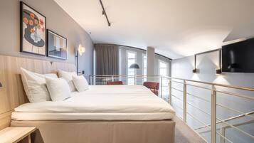 A hotel room with a bed, bedside tables, a TV, a balcony with a railing, and a window.