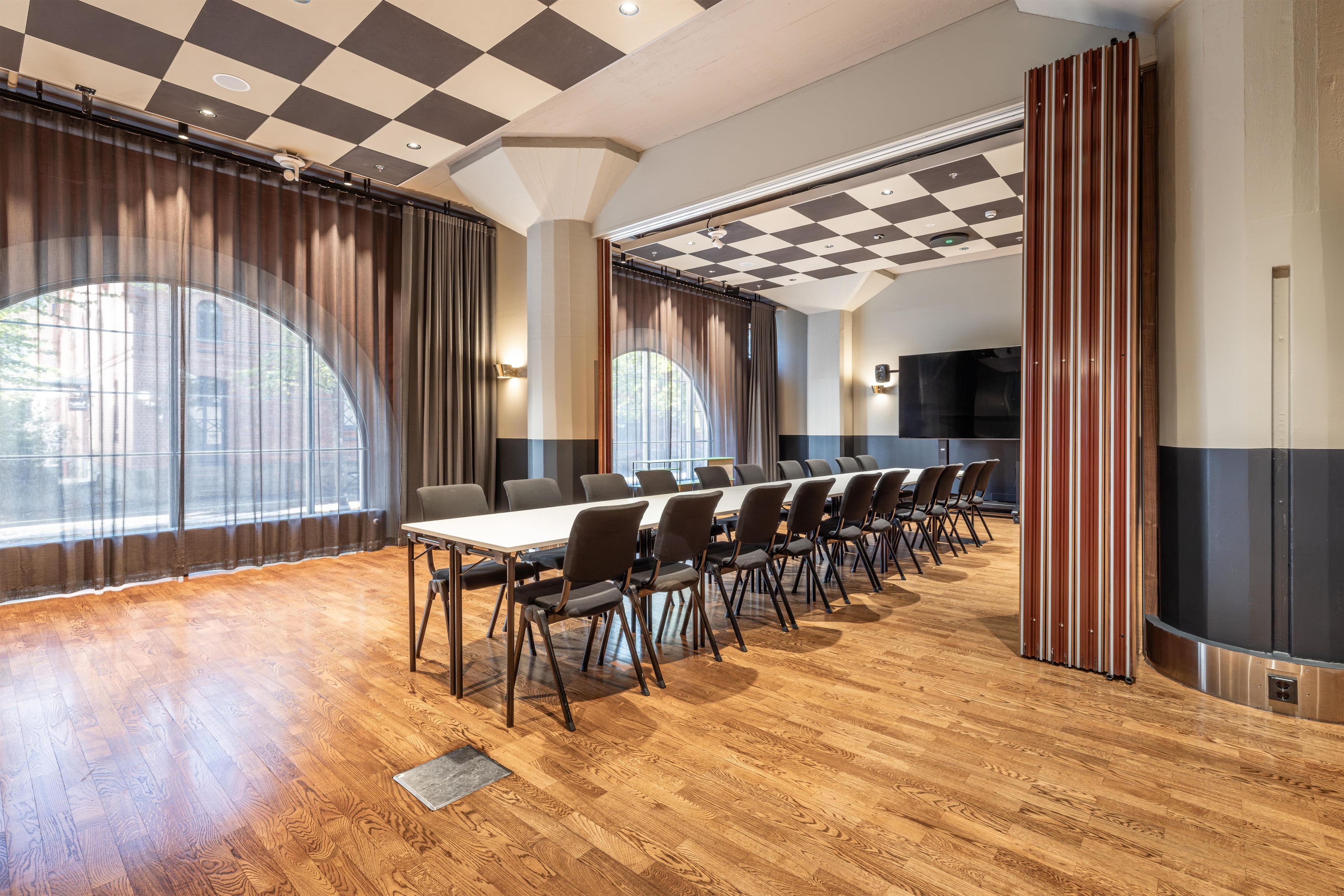 Un salón de conferencias con una mesa larga, sillas y una pantalla grande.