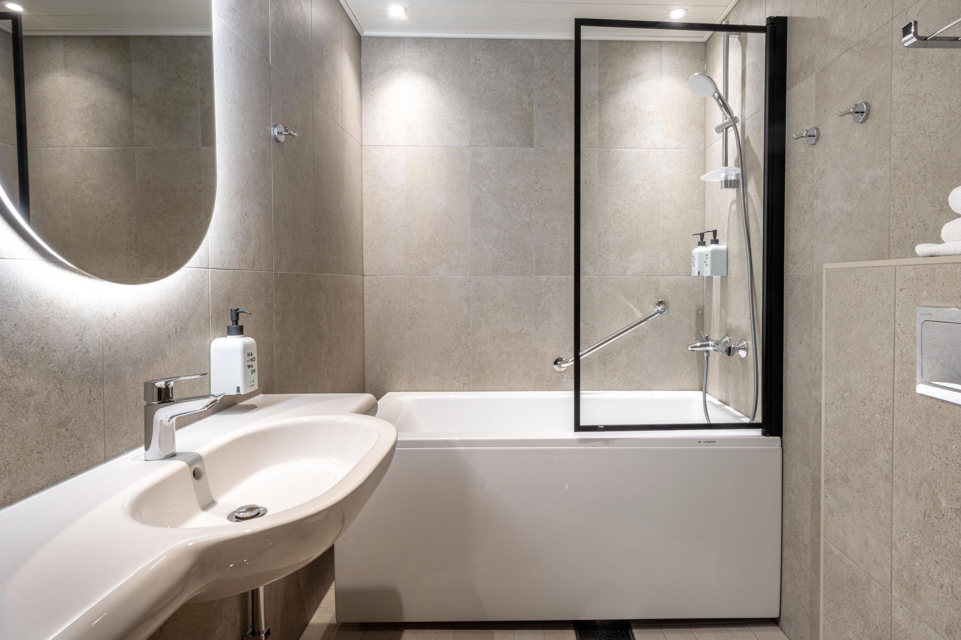 Un baño moderno con lavamanos, espejo y bañera.