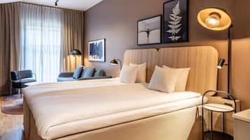 Hotellihuone, jossa on suuri sänky, työpöytä, tuoli, sohva ja näkymä ulos.