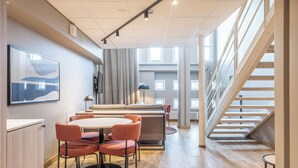 A modern interior with a dining area, a sofa, a staircase, and a large window. - Scandic Grand Marina (Helsinki)
