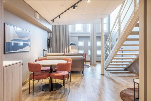A modern interior with a dining area, a sofa, a staircase, and a large window. - Scandic Grand Marina (Helsinki)