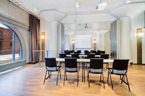 A conference room with a long table, chairs, a projector screen, and a large window with curtains. - Scandic Grand Marina (Helsinki)