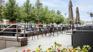 An outdoor seating area with tables and chairs, a lamp post, and umbrellas. - Scandic Grand Marina (Helsinki)