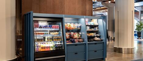 A vending machine with beverages and snacks, located in a lobby with a sign for meeting rooms.