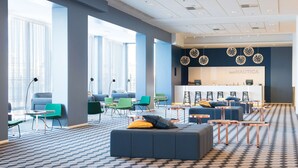 Un área de estar moderna con asientos, una recepción y ventanas amplias.