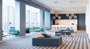 A modern lounge area with seating, a reception desk, and large windows. - Scandic Grand Marina (Helsinki)
