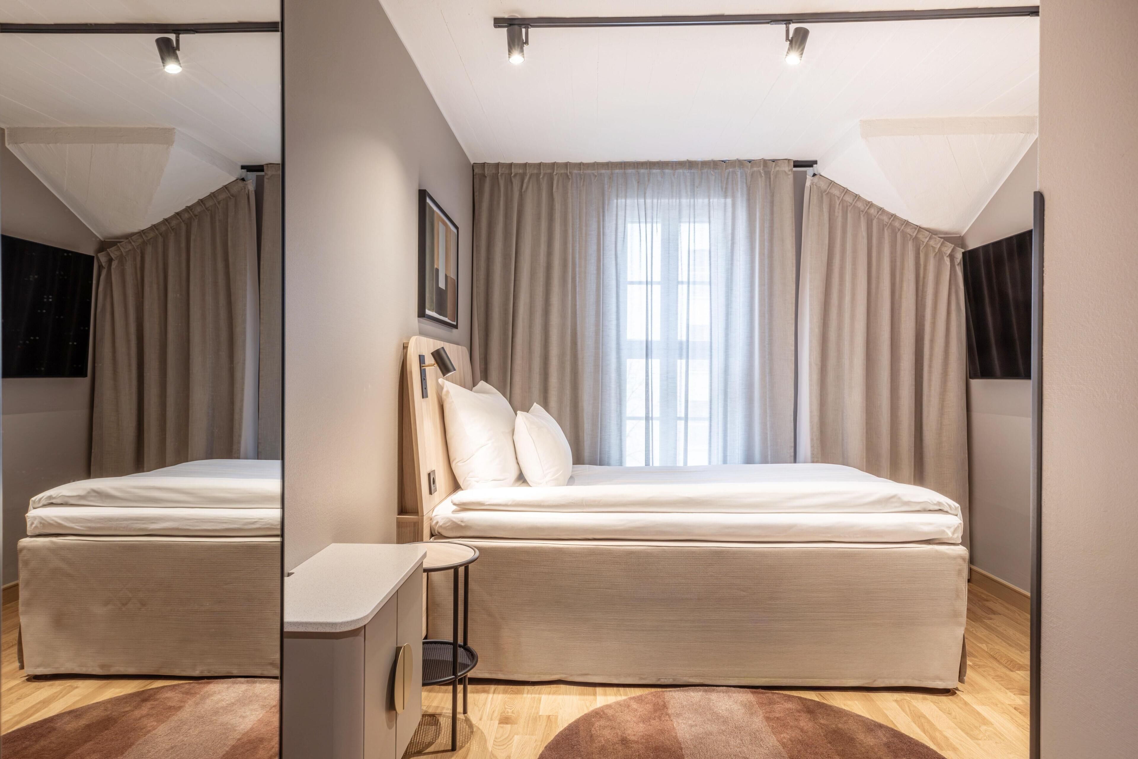 Un dormitorio moderno con una cama, mesita de noche y ventana con cortinas.