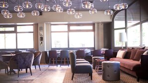 A modern interior with a dining area, seating, and large windows. - Scandic Winn (Karlstad)