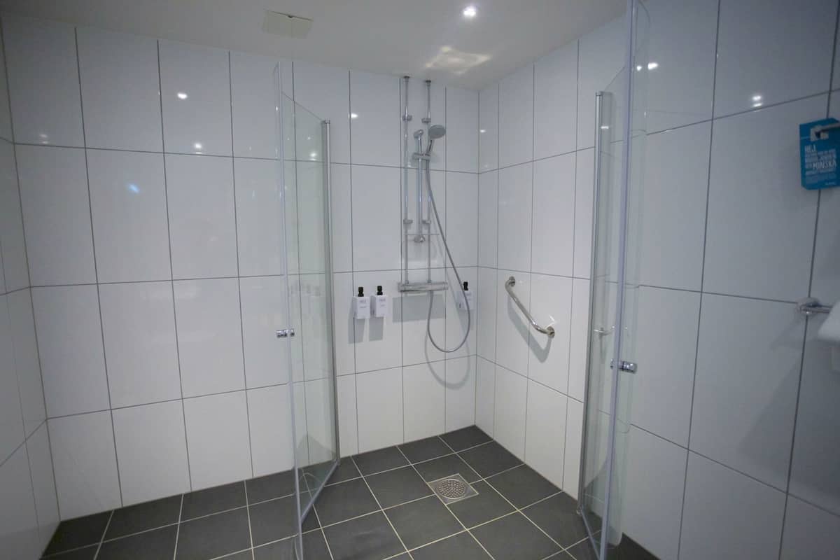 A modern shower room with glass doors, a showerhead, and a handheld shower attachment.